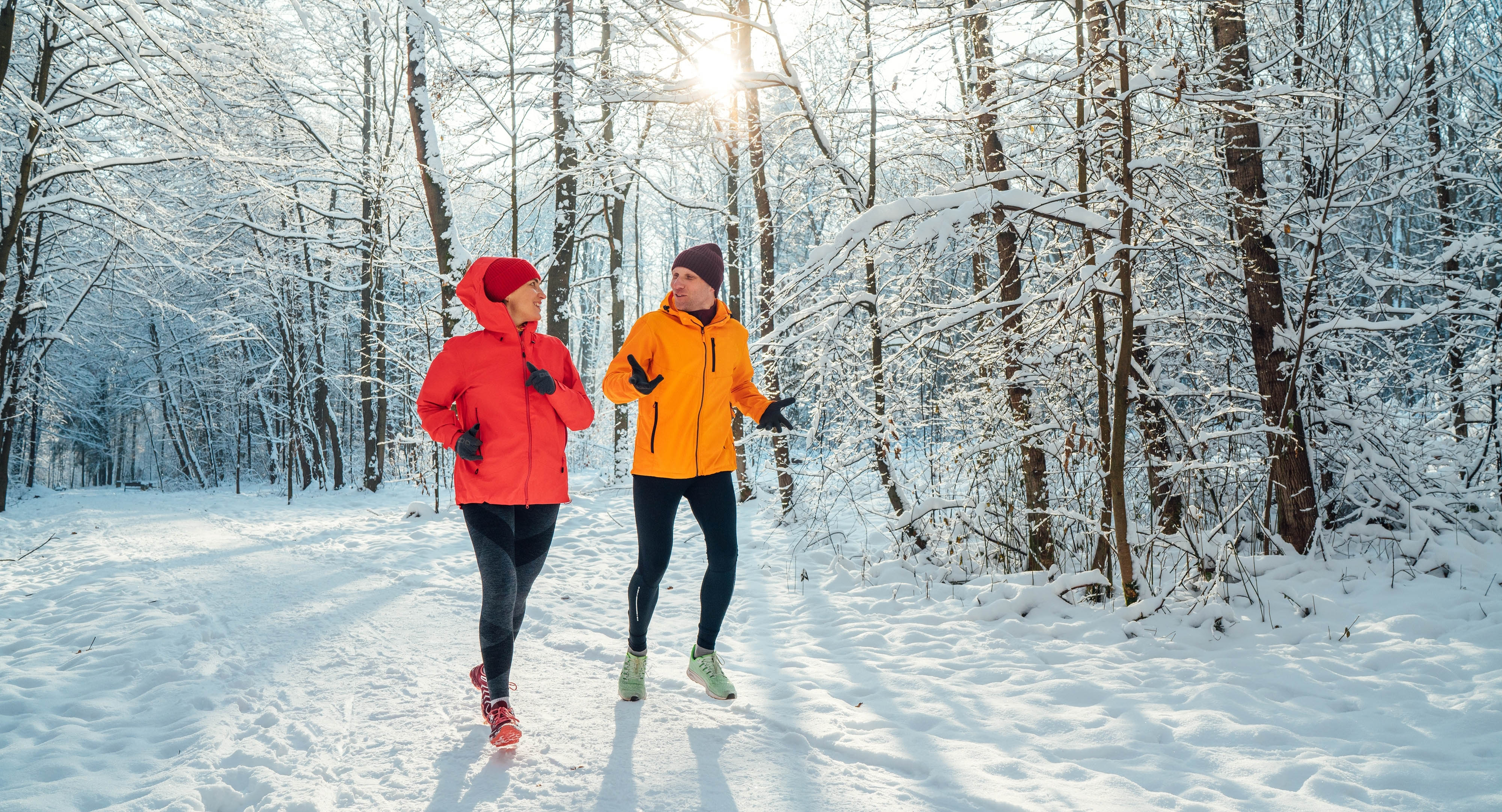 Couple running through a snowy forest together